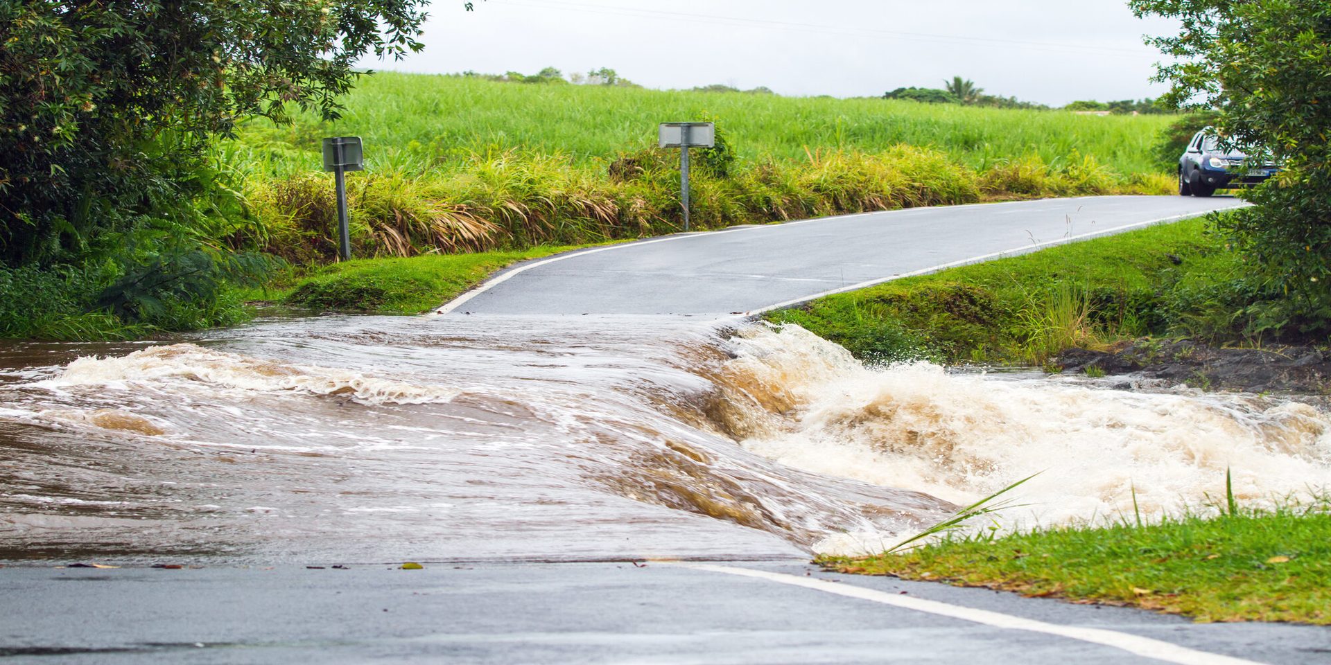Floodwater running across a rural road after heavy rain
