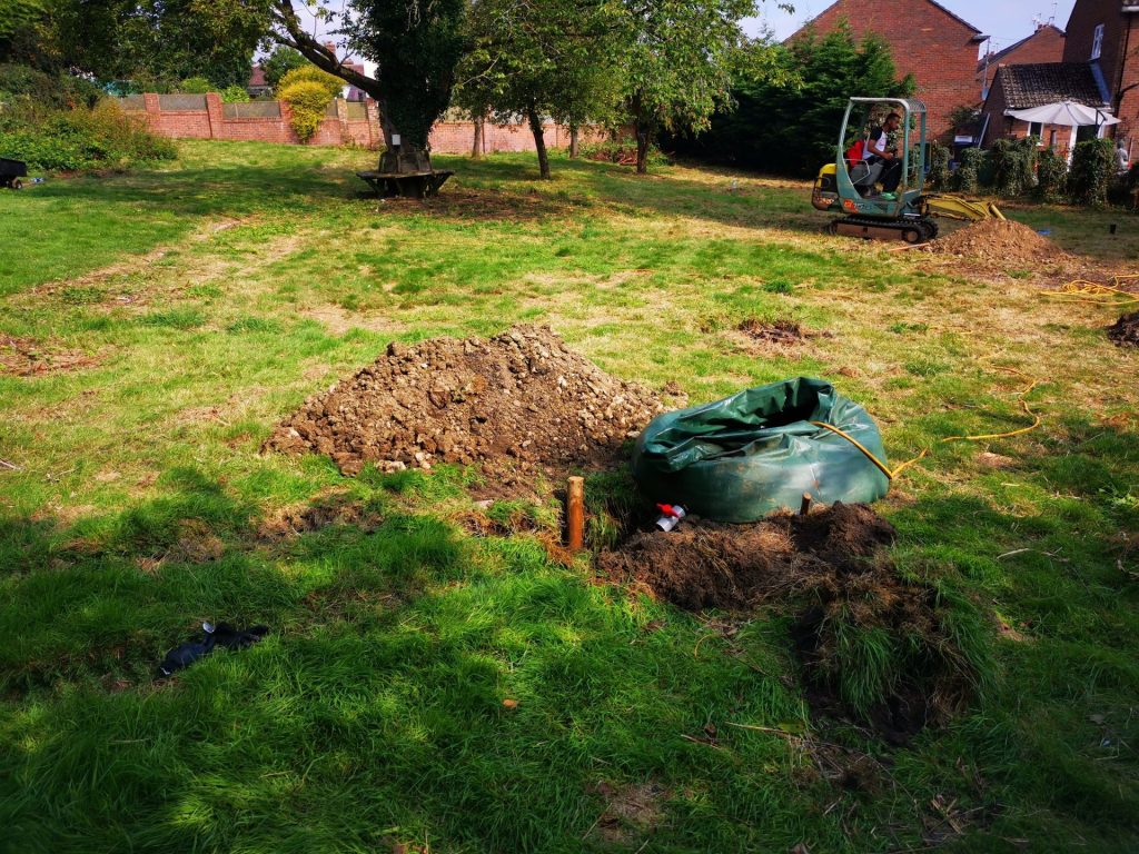 A trial pit dug for a BRE 365 percolation test, with the spoil heap, water bowser and excavator on site