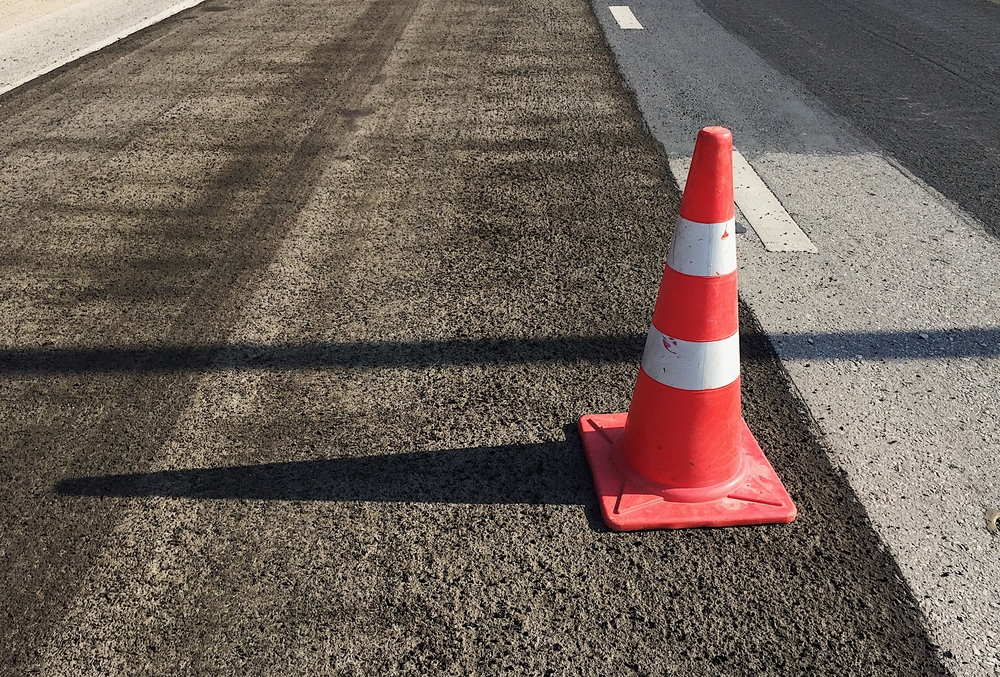 A traffic cone standing on a freshly planed carriageway alongside the running lane