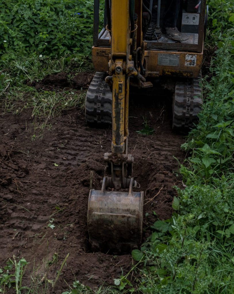 A mini excavator cutting a trial pit for a BRE 365 percolation test